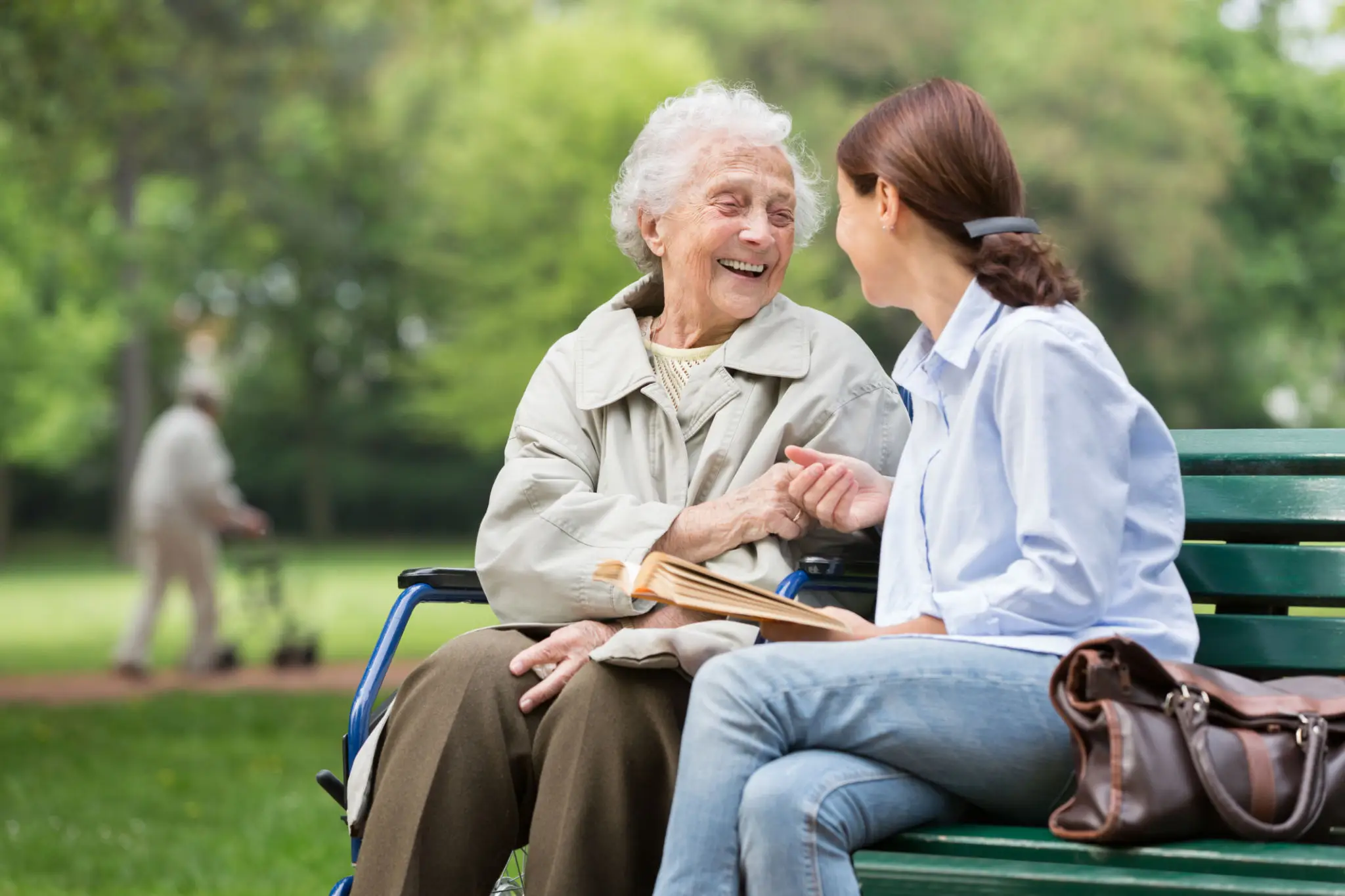 Elderly woman and young woman talking on bench.